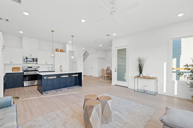 living room with light wood finished floors, recessed lighting, visible vents, a ceiling fan, and stairs