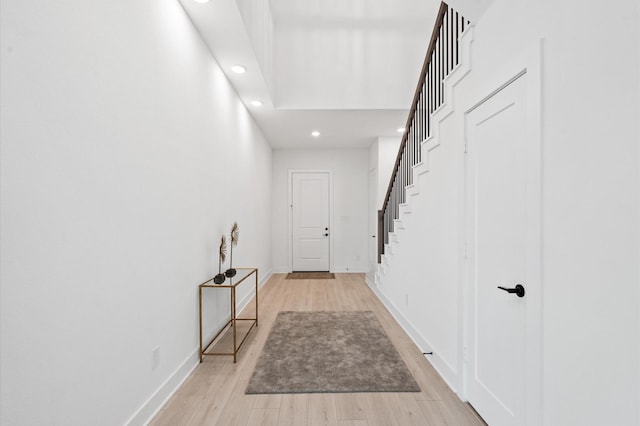 hall featuring recessed lighting, baseboards, light wood finished floors, and stairs