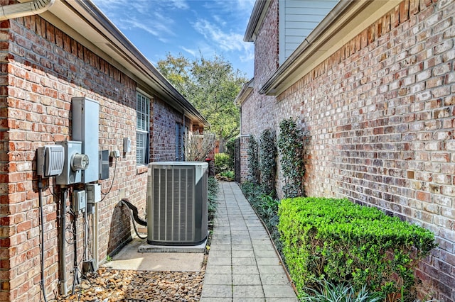 view of home's exterior with brick siding, fence, and central air condition unit