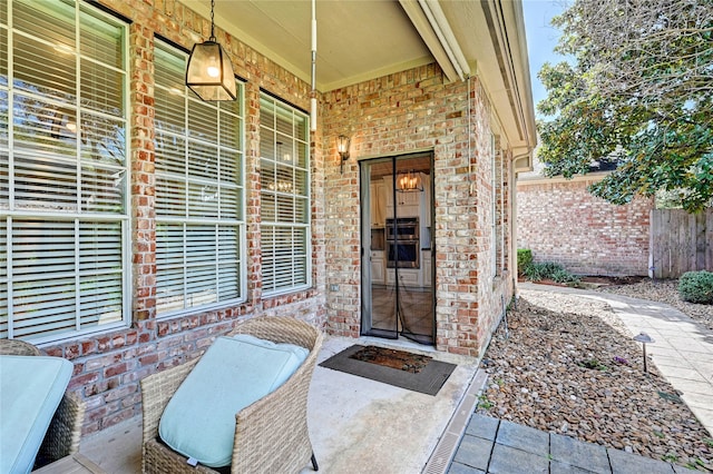 view of exterior entry with fence and brick siding