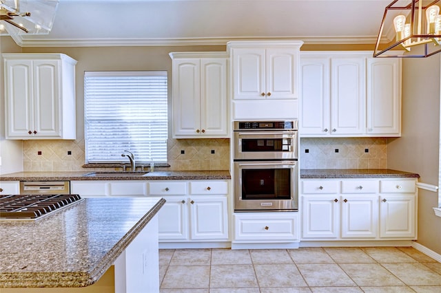 kitchen featuring stainless steel appliances, a sink, decorative light fixtures, and white cabinets