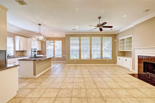 kitchen featuring double oven, a tile fireplace, visible vents, and crown molding