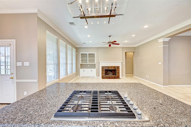 kitchen with ornamental molding, visible vents, plenty of natural light, and a tiled fireplace