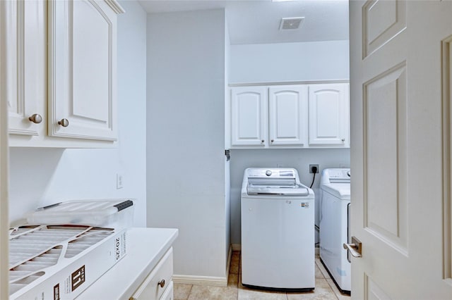 laundry area with light tile patterned floors, cabinet space, visible vents, washer and dryer, and baseboards