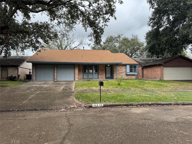 single story home with driveway, brick siding, roof with shingles, an attached garage, and a front yard