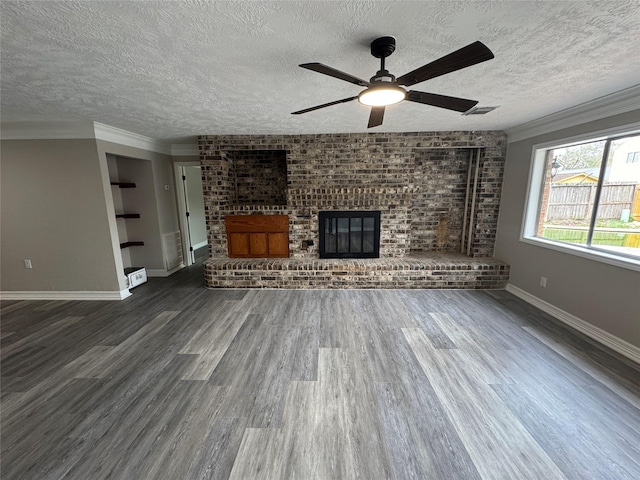 unfurnished living room featuring a textured ceiling, a fireplace, wood finished floors, visible vents, and crown molding