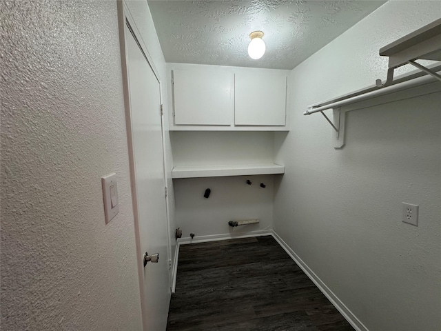 washroom featuring dark wood-style flooring, hookup for a gas dryer, cabinet space, a textured ceiling, and baseboards