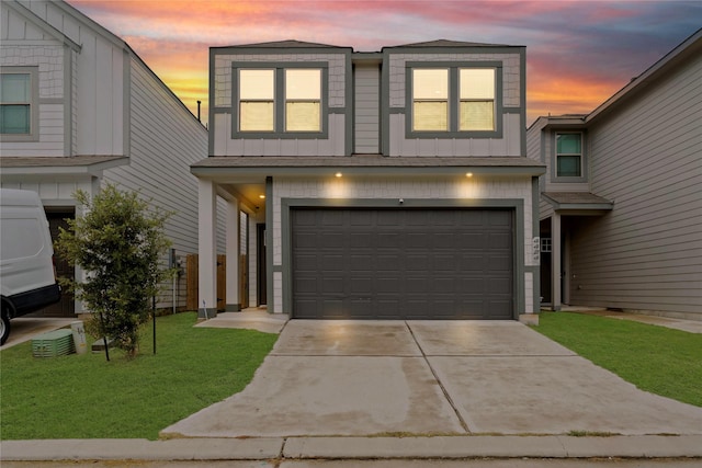 view of front facade featuring board and batten siding, a lawn, driveway, and an attached garage