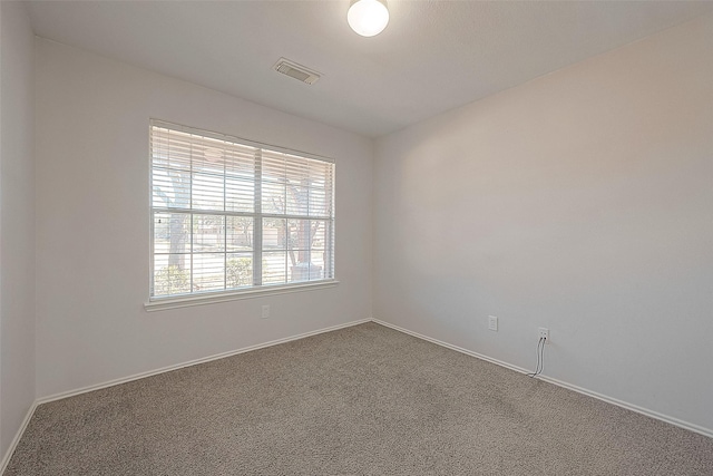 empty room with dark colored carpet, visible vents, and baseboards