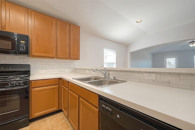 kitchen with lofted ceiling, light countertops, backsplash, a sink, and black appliances