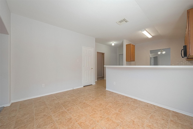 unfurnished room featuring visible vents, vaulted ceiling, and baseboards