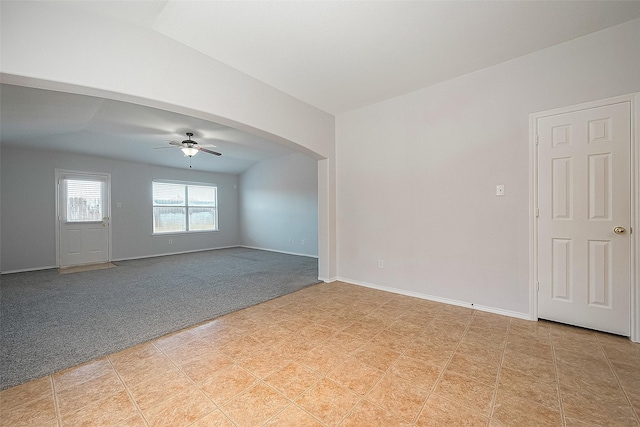 spare room with arched walkways, ceiling fan, light carpet, baseboards, and vaulted ceiling