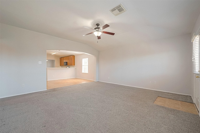 unfurnished living room featuring lofted ceiling, arched walkways, visible vents, and light colored carpet