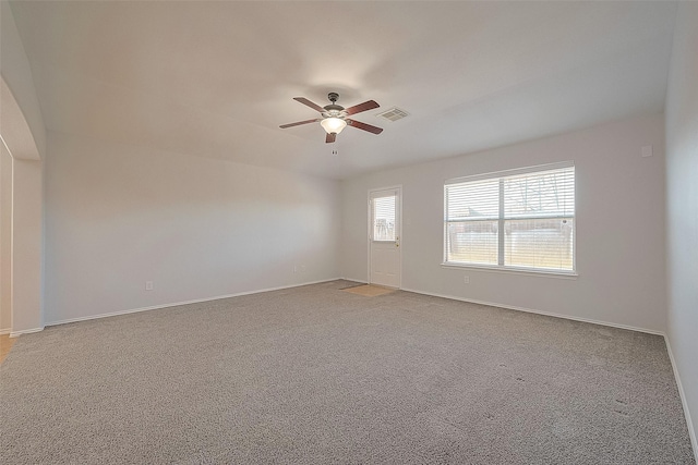 carpeted spare room featuring a ceiling fan, visible vents, and baseboards