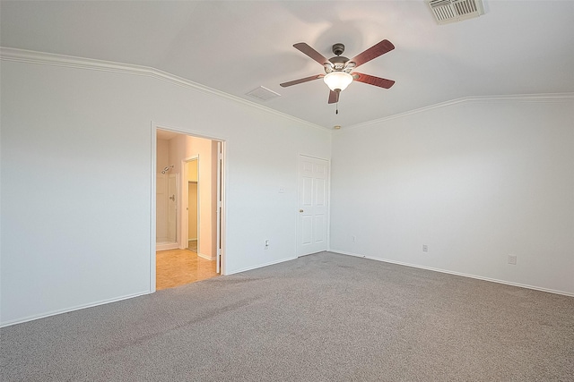 carpeted spare room with ornamental molding, visible vents, vaulted ceiling, and a ceiling fan