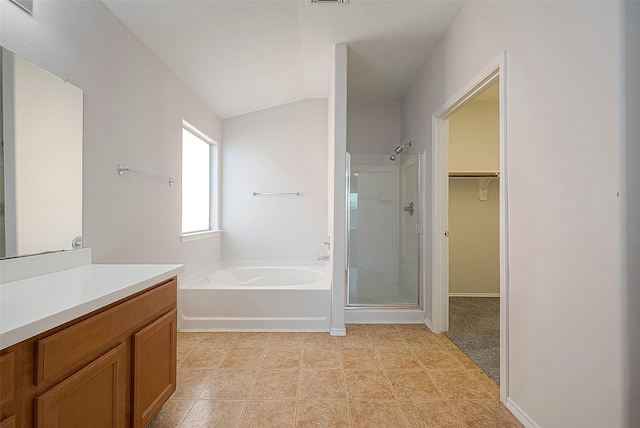 bathroom with a walk in closet, a garden tub, lofted ceiling, a stall shower, and vanity