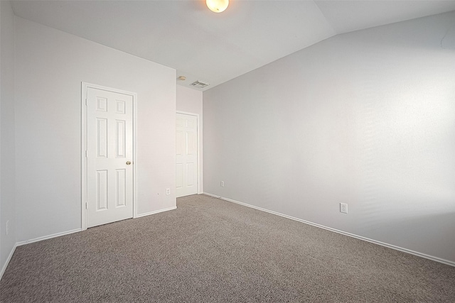 unfurnished bedroom with baseboards, visible vents, vaulted ceiling, and carpet flooring