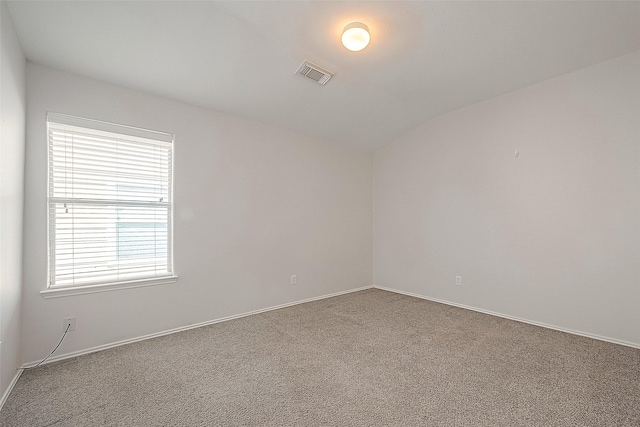 empty room featuring lofted ceiling, carpet flooring, visible vents, and baseboards