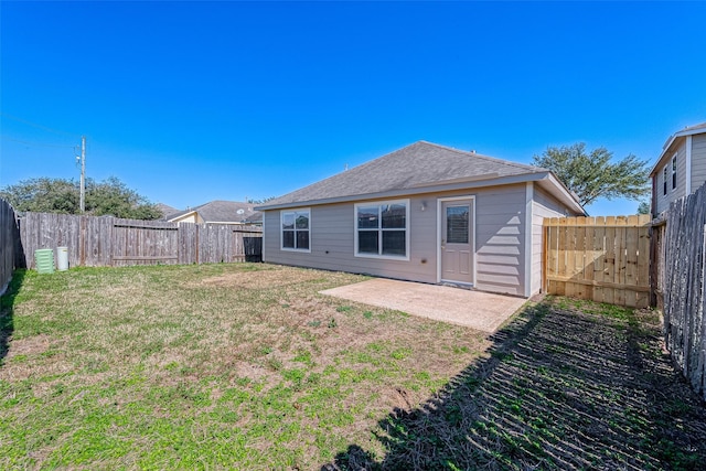 back of property with a shingled roof, a patio area, a fenced backyard, and a lawn