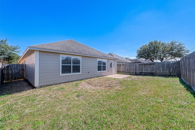 back of house featuring roof with shingles, a lawn, a patio area, and a fenced backyard