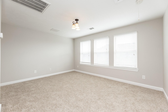 spare room featuring attic access, baseboards, visible vents, and carpet floors