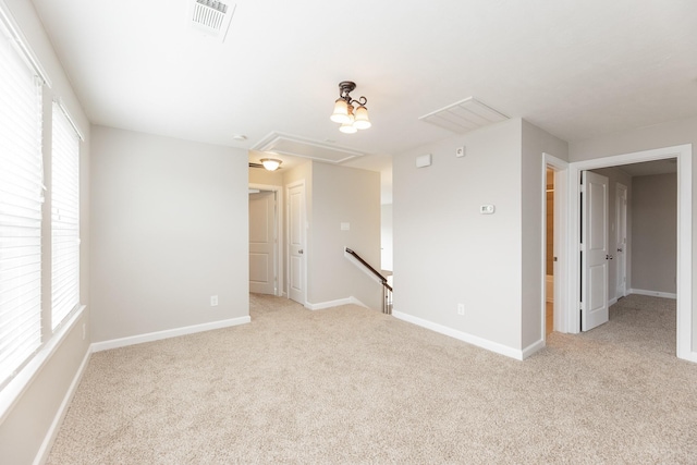 spare room with light carpet, a healthy amount of sunlight, and attic access