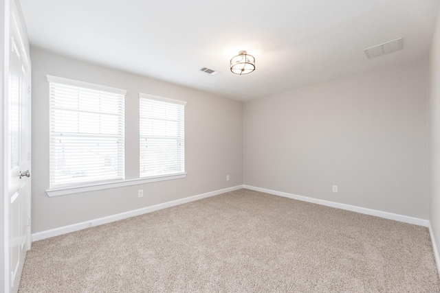 spare room featuring carpet, visible vents, and baseboards