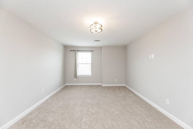 spare room featuring light carpet, visible vents, and baseboards