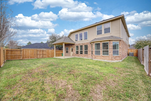 rear view of house with a yard, a patio, brick siding, and a fenced backyard