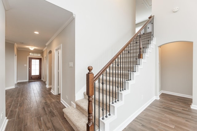 foyer with arched walkways, baseboards, and wood finished floors