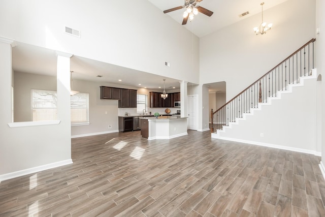 unfurnished living room featuring stairs, baseboards, visible vents, and light wood finished floors