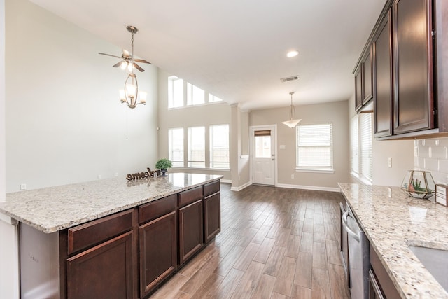 kitchen featuring a wealth of natural light, dark brown cabinets, light stone counters, and wood finished floors