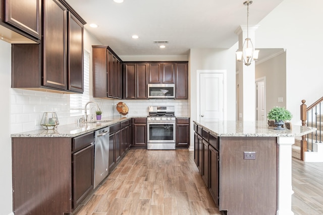 kitchen featuring a center island, dark brown cabinetry, light wood-type flooring, appliances with stainless steel finishes, and a sink