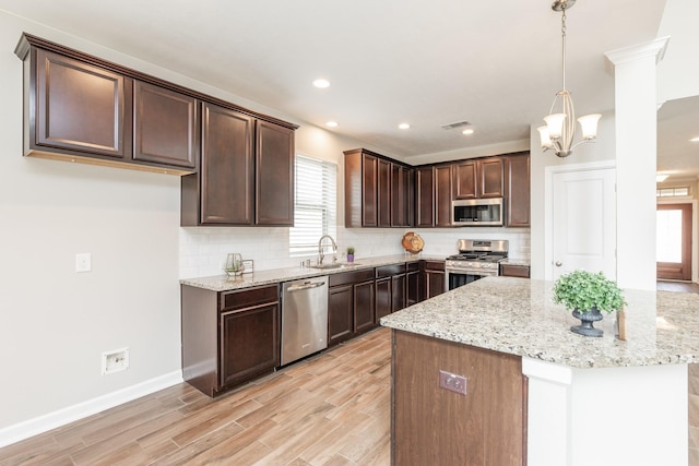 kitchen featuring dark brown cabinets, backsplash, light stone countertops, light wood-style flooring, and stainless steel appliances