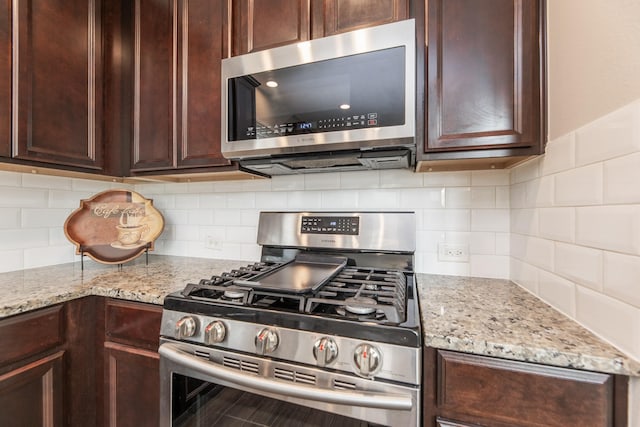 kitchen featuring backsplash, light stone counters, dark brown cabinets, and appliances with stainless steel finishes