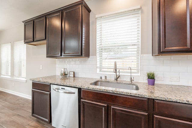 kitchen featuring a sink, stainless steel dishwasher, dark brown cabinets, and a wealth of natural light