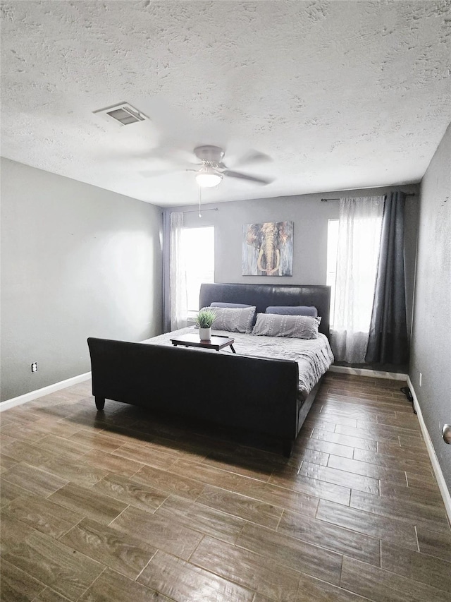 bedroom with baseboards, multiple windows, visible vents, and wood finished floors