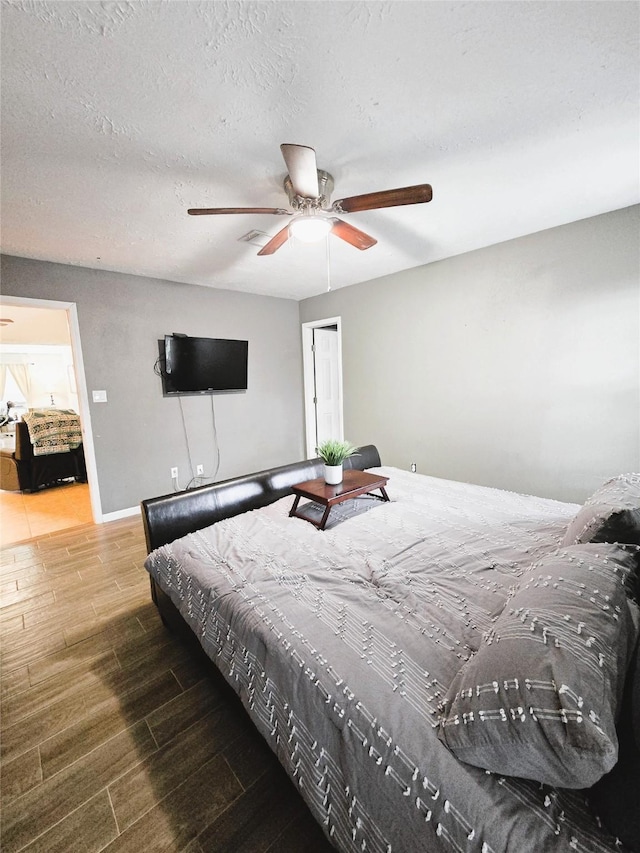 bedroom featuring a textured ceiling, wood finished floors, a ceiling fan, and baseboards