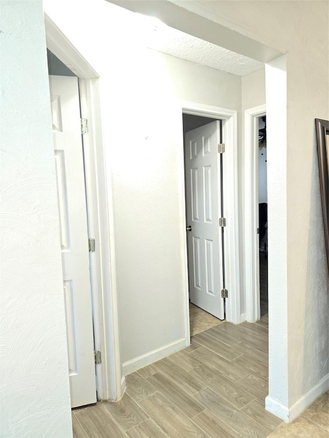 hall with baseboards and light wood-style floors