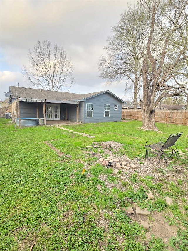 back of house with central AC, fence, a lawn, and french doors