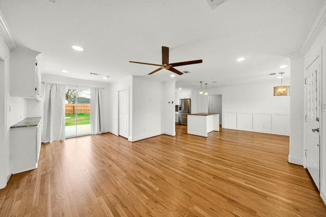 unfurnished living room with light wood finished floors, ceiling fan, crown molding, a decorative wall, and recessed lighting