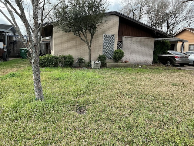 view of home's exterior with a garage, brick siding, and a lawn