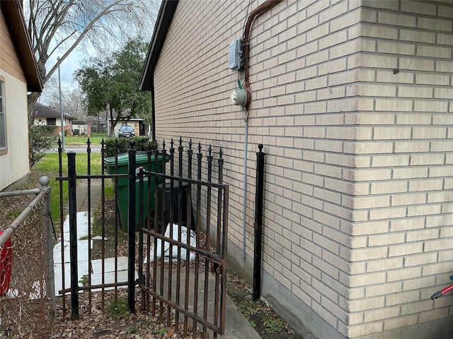 view of home's exterior with a gate, fence, and brick siding