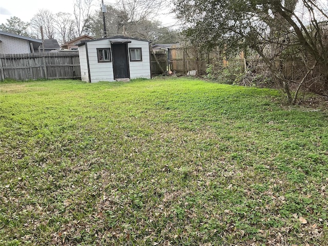 view of yard featuring a fenced backyard, a storage unit, and an outbuilding