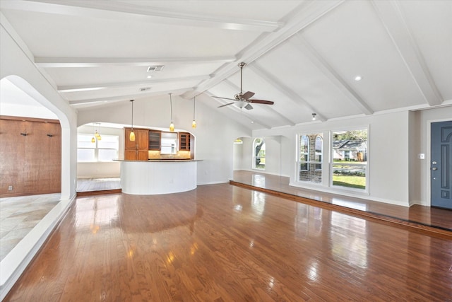 unfurnished living room with arched walkways, ceiling fan, wood finished floors, and visible vents