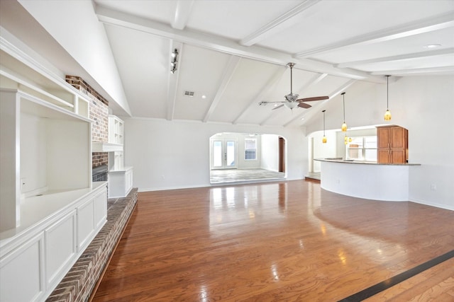 unfurnished living room featuring arched walkways, a fireplace, wood finished floors, and a ceiling fan