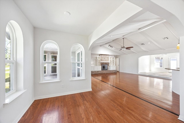 unfurnished living room with lofted ceiling with beams, a healthy amount of sunlight, visible vents, and a glass covered fireplace