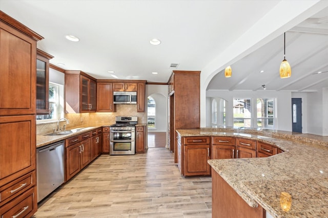 kitchen featuring light stone counters, stainless steel appliances, visible vents, a wealth of natural light, and decorative backsplash