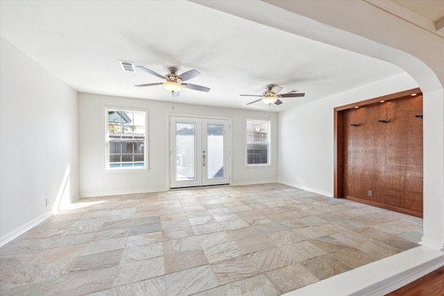 spare room with arched walkways, french doors, visible vents, and stone finish flooring