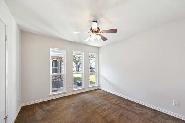 spare room featuring dark carpet, a ceiling fan, and baseboards